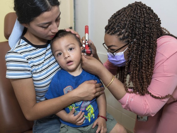 Female African-American med student examining a child ear.