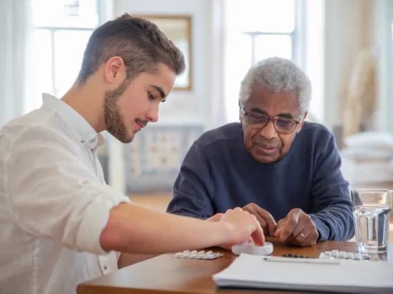 Younger man working with older person to manage medication
