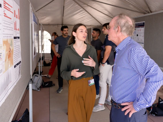 [Vivianne Benbrook, whose mentor Pathology’s Tally Largent-Milnes, PhD, targets opioid research, discusses her poster, “A Mixed-Methods Study of 20 Neonates with Opioid Exposure and Congenital Heart Disease,” with a COM-T faculty member.]