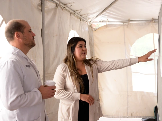 [The Department of Emergency Medicine’s Chad Viscusi, MD, listens to a student explain the research behind their poster presentation at the COM-T 2025 Research Day poster session.]