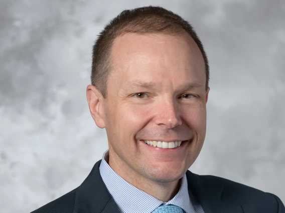 [White man wearing dark blue blazer, blue dress shirt and light blue tie in head-and-shoulders photo]