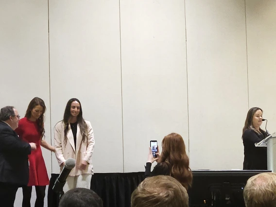 [Resident of the Year Emily Tishkoff, DO (3rd from left), a second-year resident from the DOM’s Internal Medicine Residency Program – Tucson, smiles as a photo is taken of her, with ACP Arizona Chapter governor Allan Markus, MD, MS, MBA, FACP, and 2025 ACP-AZ Scientific Meeting chair Krystal Renszel, DO, FACP, to her left and the DOM’s Joy Bulger-Beck, MD, FACP, ACP-AZ Awards Committee chair, extolling on Dr. Tishkoff to her right.]
