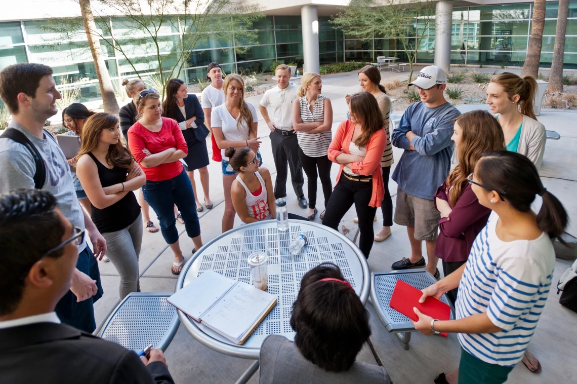 A diverse group of individuals gathered around a table, engaged in conversation and collaboration.