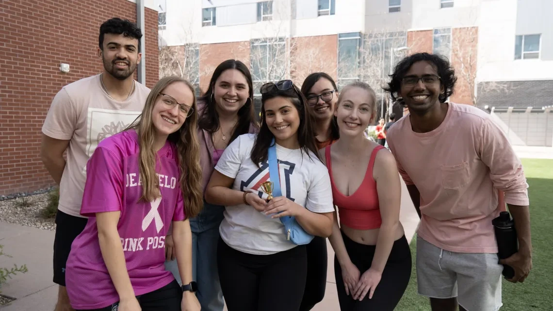 Students gather outdoors, posing for a cheerful group photo, capturing a moment of friendship and unity.