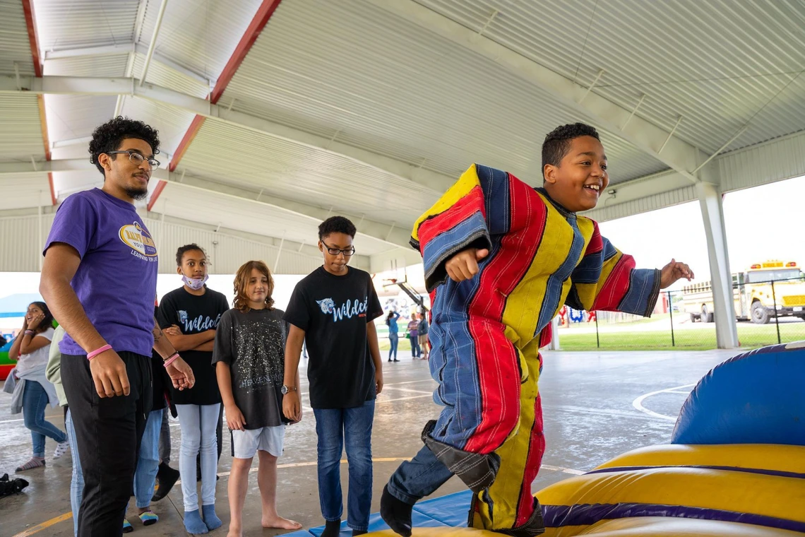 A group of children gathers around a colorful inflatable obstacle, excitedly preparing to play and explore.