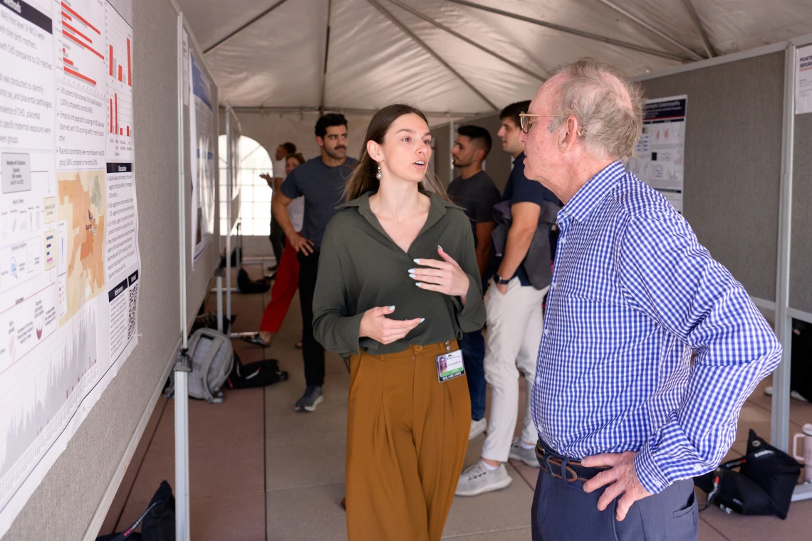 [Vivianne Benbrook, whose mentor Pathology’s Tally Largent-Milnes, PhD, targets opioid research, discusses her poster, “A Mixed-Methods Study of 20 Neonates with Opioid Exposure and Congenital Heart Disease,” with a COM-T faculty member.]