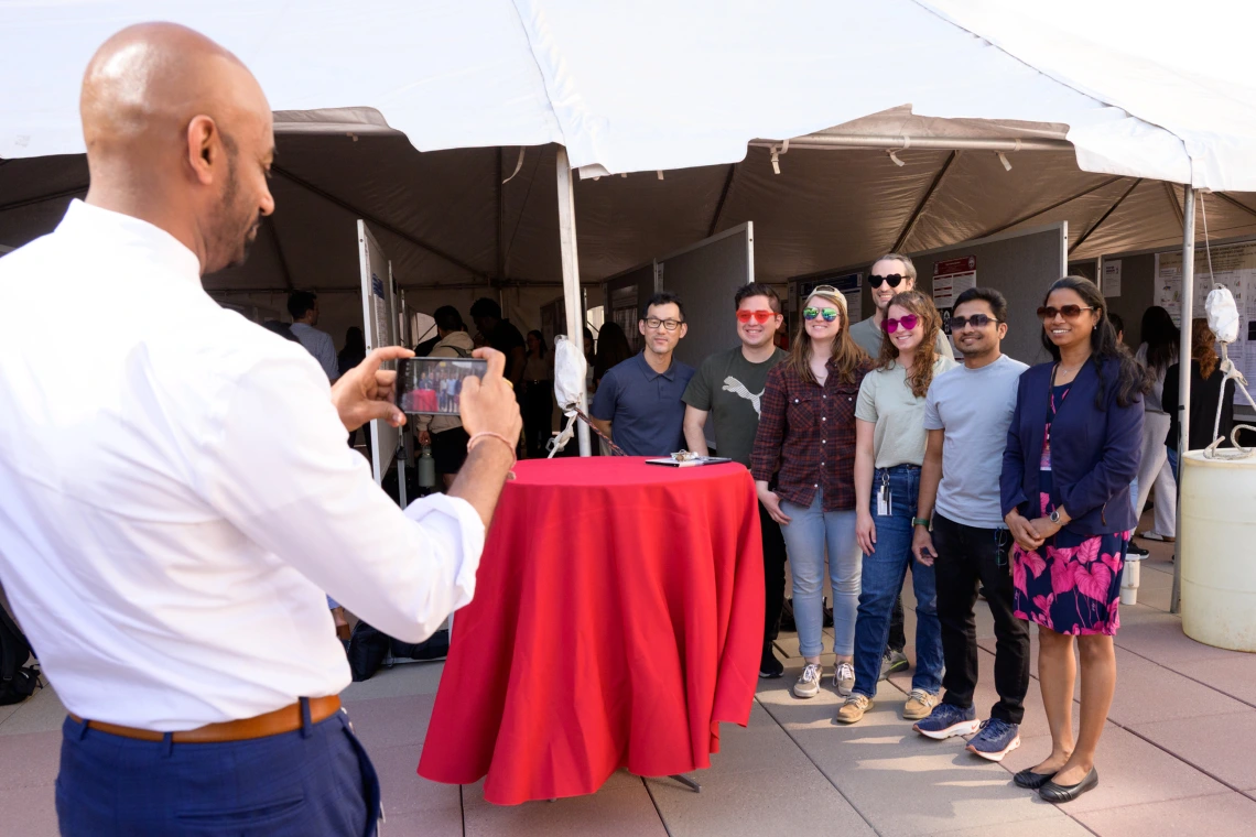 [Sakthi Sadayappan, PhD, chair of the Department of Cellular & Molecular Medicine, takes a photo of presenters from his department participating in the COM-T 2025 Research Day poster session.]