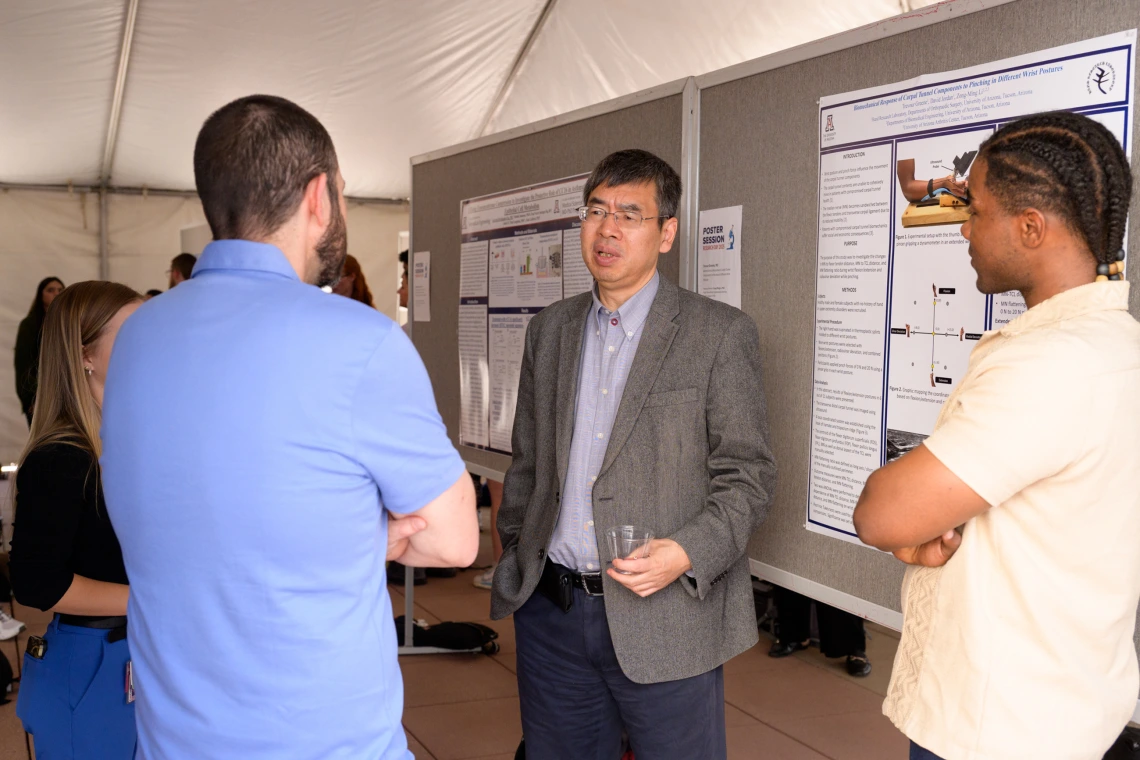 [Zong-Ming Li, PhD, the William and Sylvia Rubin Chair of Orthopedic Research at COM-T and associate director of the Arizona Arthritis Center, led by the DOM's C. Kent Kwoh, MD, discusses a poster he assisted on about carpal tunnel syndrome with co-authors Trevour Greene (right), a research lab manager, and David Jordan, PhD, MS.]