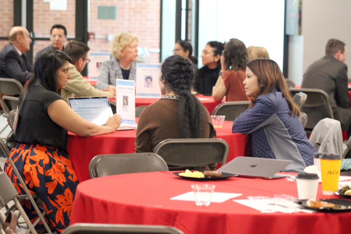 [During the Vice Chair Roundtable portion of the New Faculty Retreat, Serena Scott, MD, MBA (at left, pointing at laptop screen), speaks with Shagun Singh, MD, and Monisha Das Ireland, MD. At the table behind them are DOM vice chair of research Janet Funk, MD, speaking with Anna Morenz, MD, MPH, Susan Favour, MD, and DOM biostatistician Maryam Emami, PhD. And behind them are Joe Alpert, MD, vice chair of faculty promotions & appointments.]
