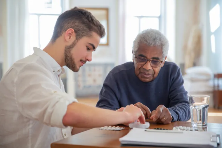 Younger man working with older person to manage medication Younger man working with older person to manage medication