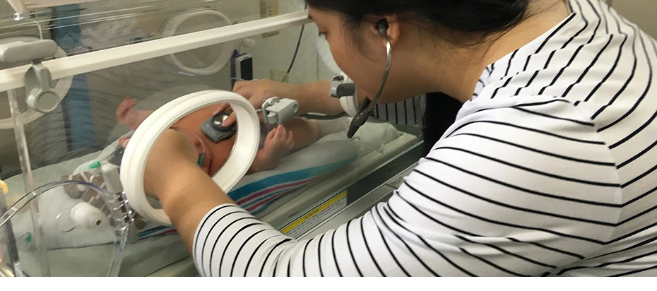 doctor with infant in incubator